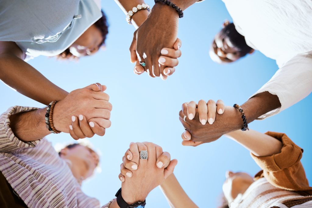 Diversity, support and people holding hands in trust and unity for community against sky background. Hand of diverse group in solidarity for united team building collaboration and teamwork success.